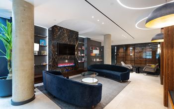 the lobby of a hotel with couches and a fireplace